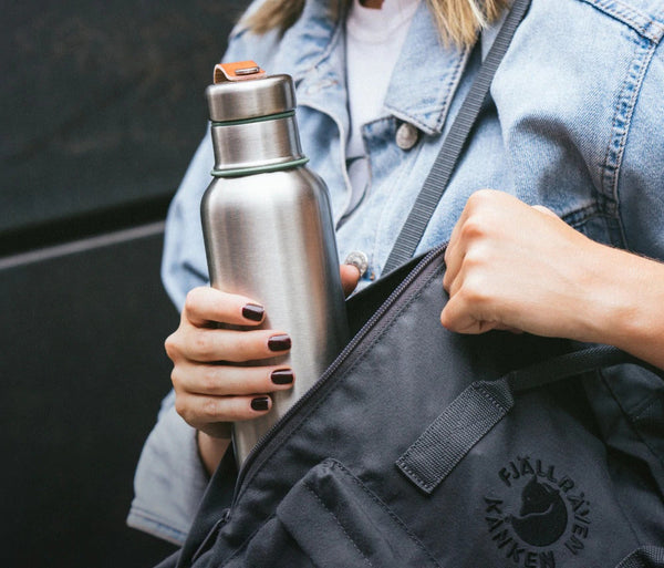 Black and blum stainless steel insulated water bottle being put into bag