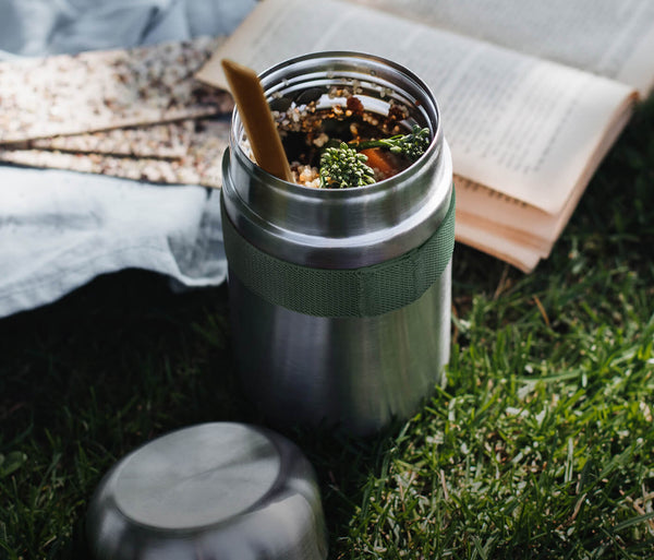 insulated food flask in a park with a book